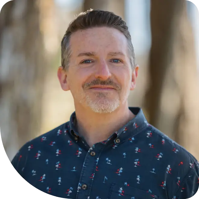 A man with a beard and mustache wearing a blue shirt.